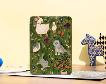 May include: A postcard with a green background featuring a white goose with a blue bow tie, a small white goose, three gray cats, and a small orange tree with red fruit. The postcard has a white border.