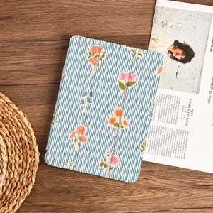 May include: A rectangular tablet case featuring a light blue and white vertical striped pattern decorated with small, colorful floral illustrations in shades of pink, orange, and blue, with a smooth, matte finish and rounded corners.