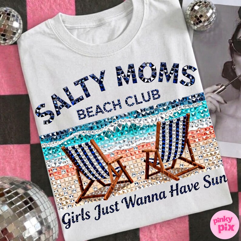 May include: White t-shirt with the text "Salty Moms Beach Club Girls Just Wanna Have Sun" in blue. The design features two beach chairs, a beach scene, and sparkling accents.