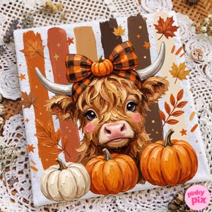 May include: A white t-shirt featuring a graphic of a fluffy brown Highland cow with a plaid bow between its horns, surrounded by orange and brown vertical brushstrokes, falling autumn leaves, and three pumpkins in white and orange colors.