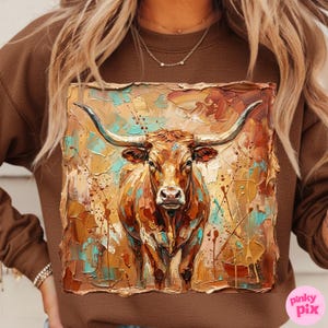 May include: Brown sweatshirt featuring a textured, colorful painting of a longhorn steer. The artwork uses shades of brown, gold, and teal, with visible brushstrokes. The steer is centered, facing forward, with large horns.