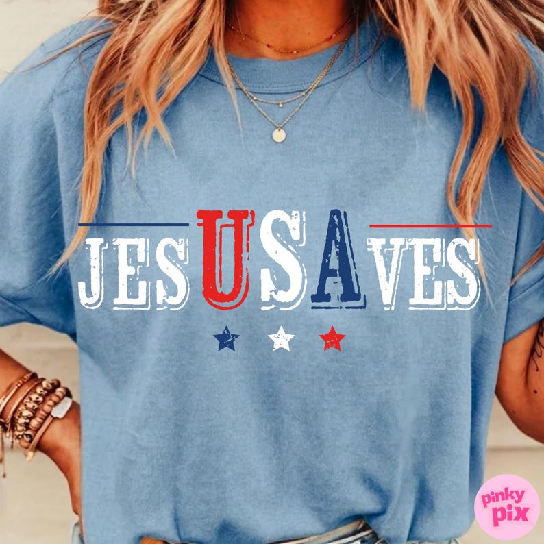 May include: Light blue t-shirt with the text "JESUSAVES" in red, white, and blue, with three stars below. The shirt has a crew neck and short sleeves. The design is patriotic.