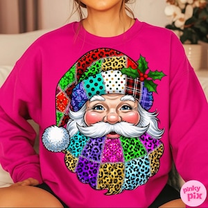 Könnte beinhalten: Ein magenta Sweatshirt mit einem farbenfrohen Weihnachtsmann-Motiv. Das Santa-Design hat einen Patchwork-Hut und Bart mit Leopardenmuster und Tupfen. Stechpalmenblätter und Beeren schmücken den Hut. Das Design ist mittig auf der Vorderseite des Sweatshirts platziert.