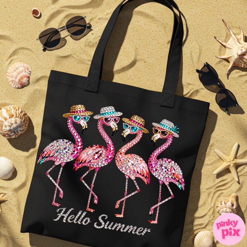 May include: Black tote bag featuring four pink flamingo illustrations wearing sunglasses and hats. The words "Hello Summer" are written in a decorative font. The bag is on a sandy surface with sunglasses and seashells.