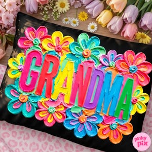 May include: Black pillow with the word "GRANDMA" in colorful, raised lettering, surrounded by vibrant, textured flowers in shades of pink, yellow, blue, and orange. The pillow has a textured appearance, suggesting a painted or embroidered design.
