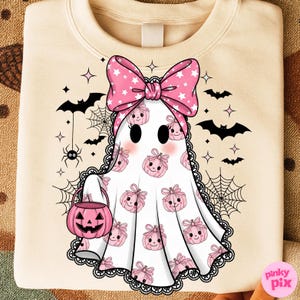 May include: Cream-coloured sweatshirt with a ghost design. The ghost has a pink bow with white stars and carries a pink pumpkin bucket. The ghost's body is covered in pink pumpkin graphics. Black bats, spiders, and spiderwebs decorate the background.