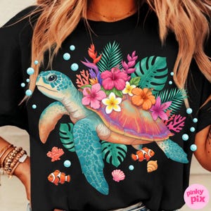 May include: Black t-shirt featuring a colorful sea turtle design. The turtle has a blue shell and is adorned with tropical flowers and leaves. The design includes orange clownfish, coral, and bubbles.