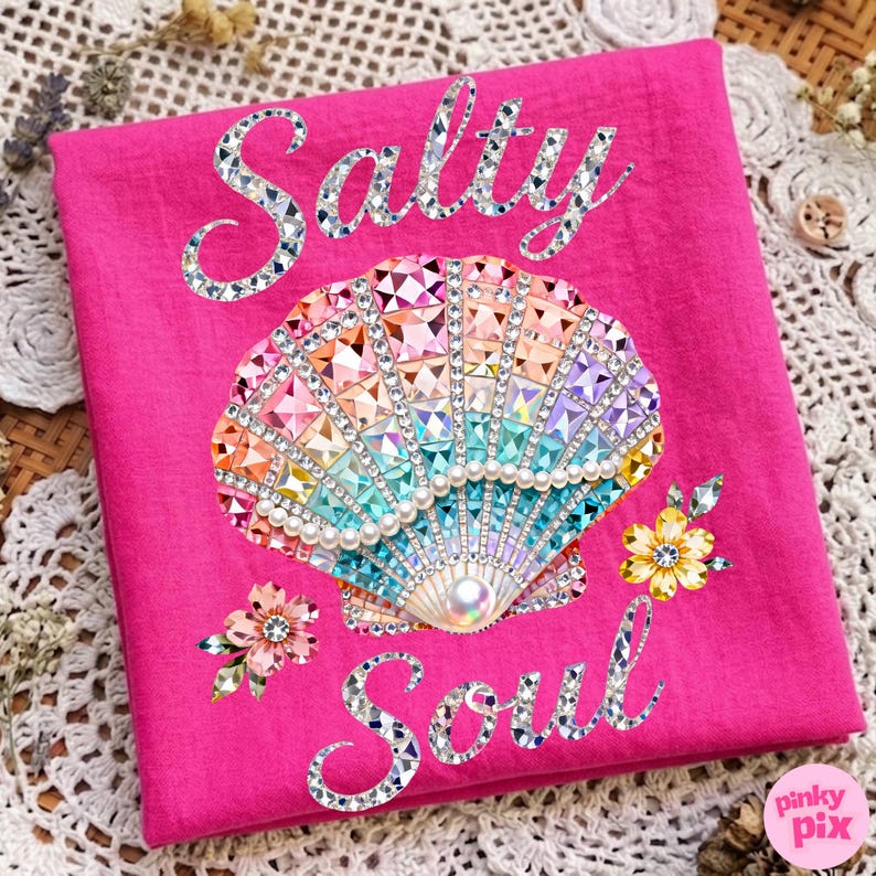 May include: A hot pink square textile features a bejeweled seashell design with the words "Salty Soul". The seashell is adorned with colorful crystals and pearls. Floral accents are placed around the seashell.