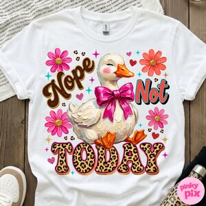 May include: White t-shirt with a graphic of a duck wearing a pink bow, surrounded by flowers and hearts. The words "Nope Not Today" are displayed in a playful font with leopard print accents. A fun, whimsical design.