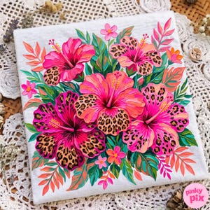 May include: A white t-shirt featuring a vibrant floral design. The design showcases large pink and orange hibiscus flowers with leopard print centers, surrounded by green leaves and smaller pink flowers. The overall theme is tropical.