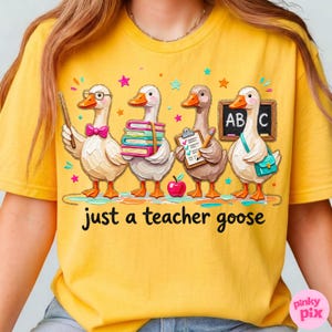 May include: Yellow t-shirt with a whimsical design featuring four cartoon geese dressed as teachers. One goose holds a pointer, another books, a third a clipboard, and the last a chalkboard. The text "just a teacher goose" is below the geese.