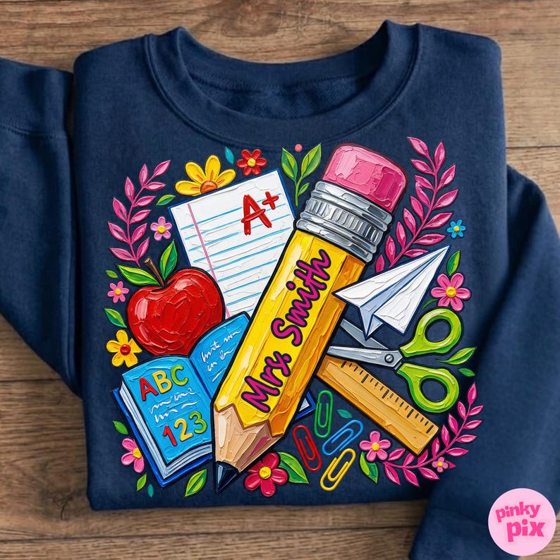 Pu&ograve; includere: Felpa blu navy con una grafica colorata a tema scolastico. Il design include una grande matita gialla con la scritta "Mrs. Smith", una mela, un libro aperto e altri materiali scolastici. Il design &egrave; circondato da fiori.
