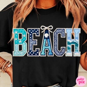 May include: Black t-shirt with the word "BEACH" in a decorative, patchwork style. The letters are various shades of blue and white, with seashell and wave patterns. The letter "A" features a seashell.