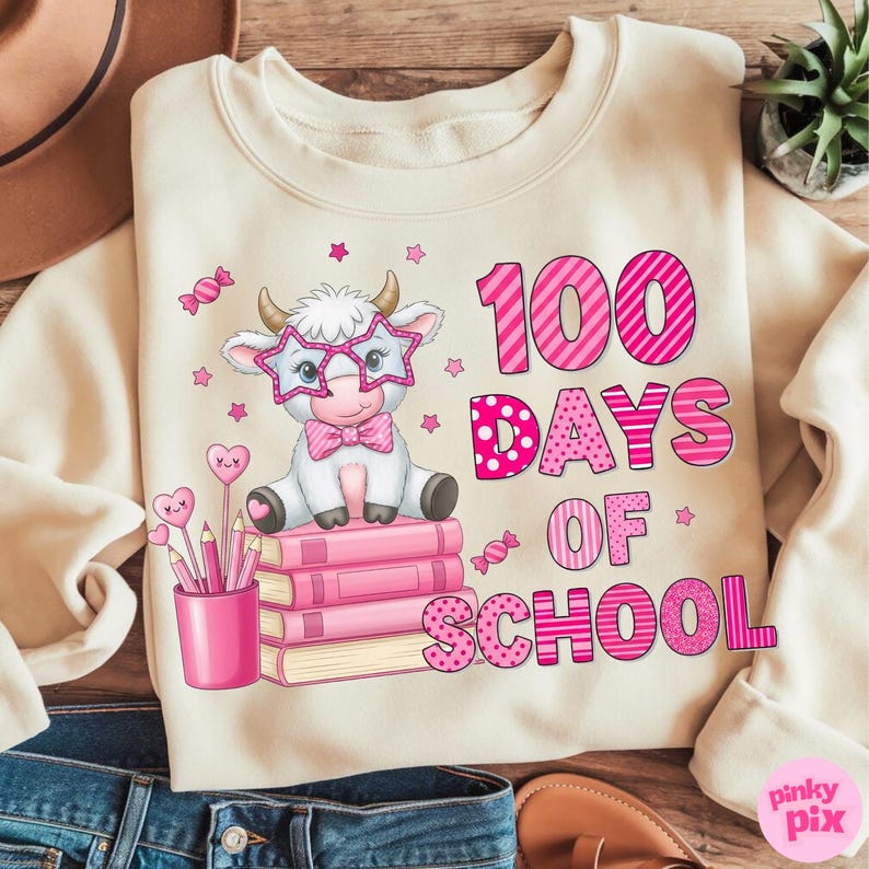 Pu&ograve; includere: Felpa color crema con una grafica raffigurante una mucca dei cartoni animati con occhiali a forma di stella e un papillon, seduta su libri rosa. Il testo "100 DAYS OF SCHOOL" &egrave; in rosa. &Egrave; presente anche un portapenne con matite a forma di cuore.