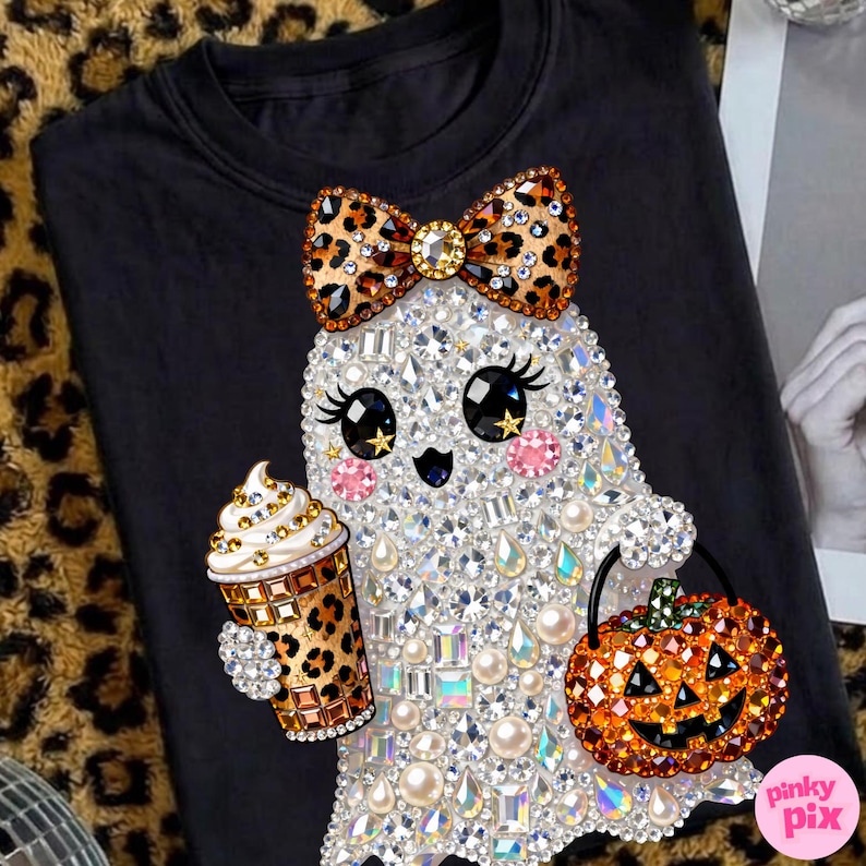 Może przedstawiać: Czarny t-shirt z grafiką ducha ozdobioną przezroczystymi, opalizującymi i r&oacute;żowymi cyrkoniami. Duch ma kokardę w panterkę, trzyma kubek do kawy w panterkę i niesie wiaderko w kształcie dyni z pomarańczowymi cyrkoniami.