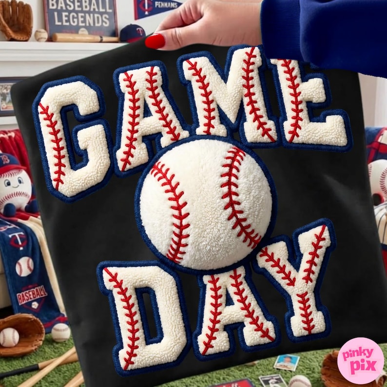 May include: Black square pillow with the words "GAME DAY" in white, with red stitching and a baseball in the center. The letters and baseball have a textured, fuzzy appearance. The pillow is a baseball-themed decorative item.
