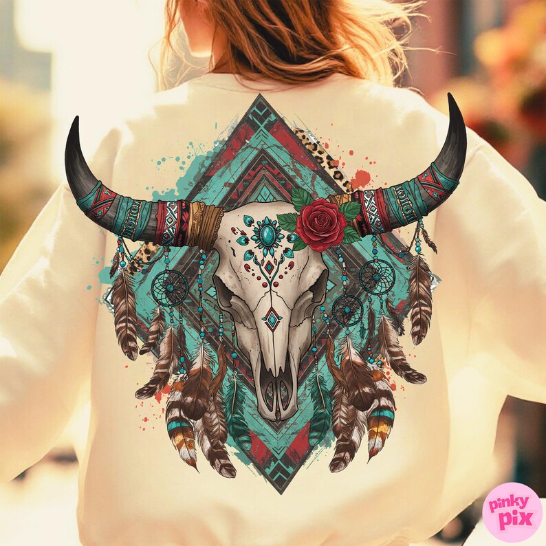 May include: Cream-coloured sweatshirt with a detailed graphic of a bull skull with long, curved horns. The design incorporates turquoise, red, and brown elements, including feathers, a rose, and geometric patterns. The overall theme is bohemian and southwestern.