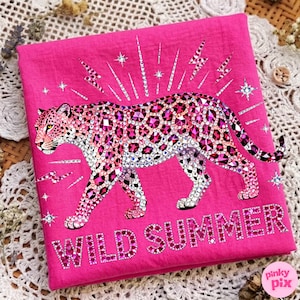May include: A hot pink textile featuring a bedazzled leopard design. The leopard is adorned with pink and clear rhinestones, with a matching text that reads "WILD SUMMER". The design includes star and lightning bolt accents.