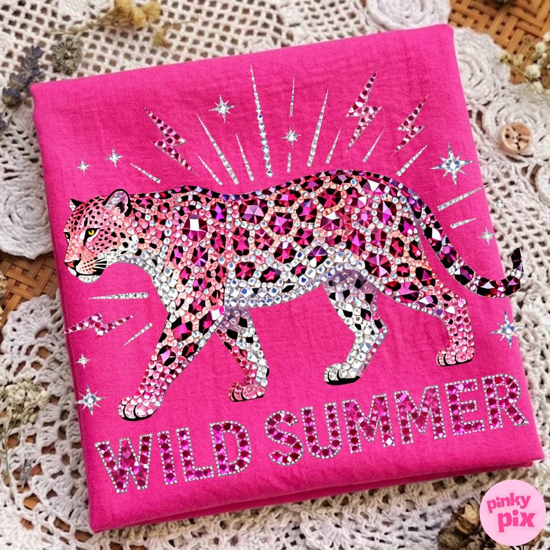May include: A hot pink textile featuring a bedazzled leopard design. The leopard is adorned with pink and clear rhinestones, with a matching text that reads "WILD SUMMER". The design includes star and lightning bolt accents.