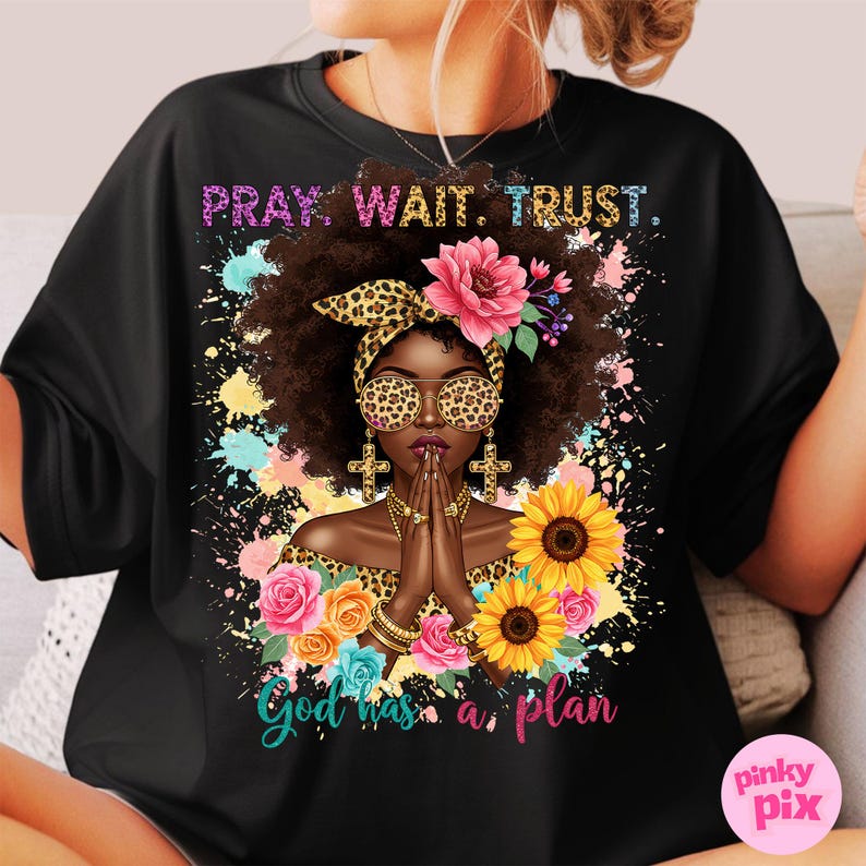 May include: Black t-shirt with a colorful illustration of a woman with a crown of flowers and the text "Pray. Wait. Trust. God has a plan."