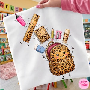 Può includere: Una borsa tote bianca con una colorata illustrazione a cartoni animati di materiale scolastico con motivi leopardati, tra cui uno zaino, un righello, un quaderno, una colla stick, una matita, un temperino, una gomma e un evidenziatore rosa sorridenti.