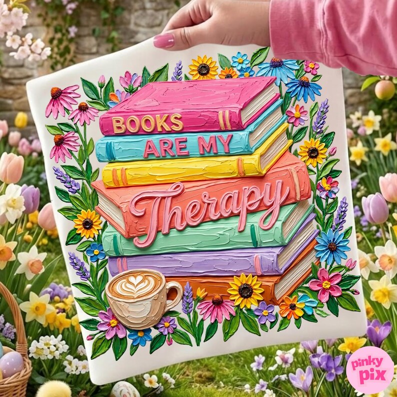 May include: A decorative square pillow featuring a stack of colorful books with the words "BOOKS ARE MY THERAPY." The design includes a coffee cup and is surrounded by flowers in a garden setting.