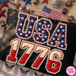 Pode incluir: Almofada preta com o texto "USA 1776" em vermelho, branco e azul, com uma borda de renda. As letras e os números são preenchidos com um padrão de estrelas. Uma bandeira americana e decorações patrióticas estão no fundo.