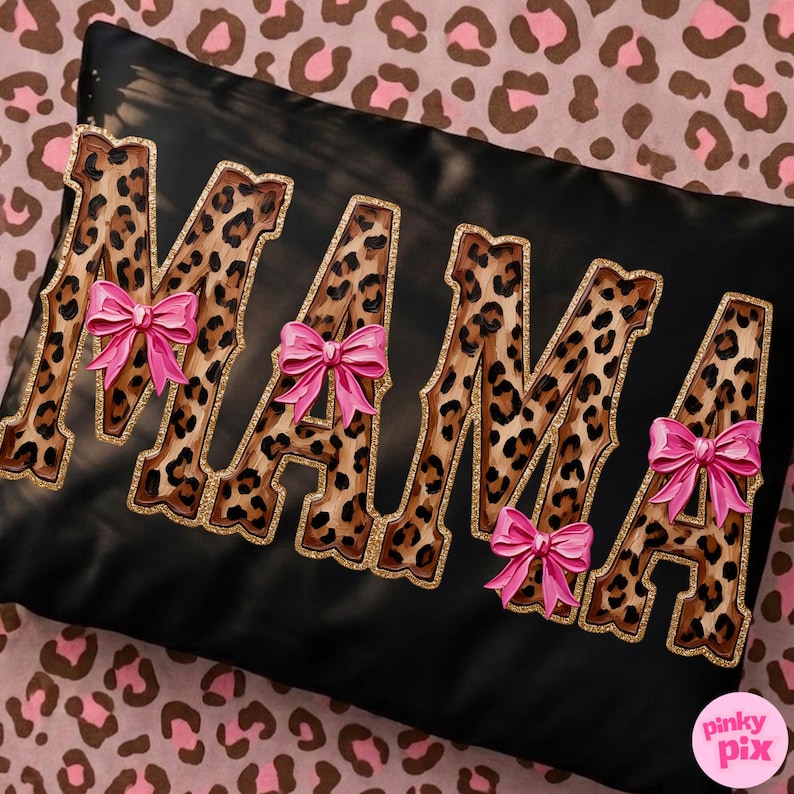 May include: Black decorative pillow with the word "MAMA" in leopard print letters outlined in gold glitter. Each letter has a pink bow. The pillow is on a pink and brown leopard print background.