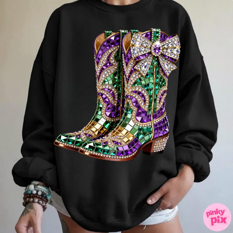 May include: Black sweatshirt featuring a vibrant graphic of jeweled cowboy boots. The boots are adorned with purple, green, and gold mosaic-style embellishments, and a large, sparkling bow. The design is detailed with rhinestones.