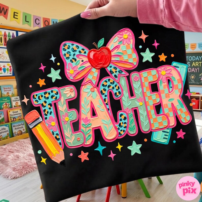 May include: Black pillowcase with a colorful "TEACHER" design. The design includes a bow with a leopard print, an apple, flowers, stars, and a pencil. The word "TEACHER" is in a layered, 3D style with floral and checkered patterns.