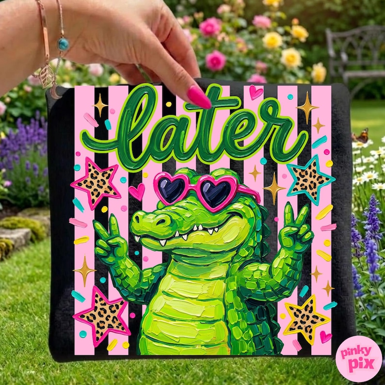 May include: A black square towel with a vibrant graphic featuring a green alligator wearing heart-shaped sunglasses and giving a peace sign. The word "Later" is written in green script above the alligator, with pink and black striped background.