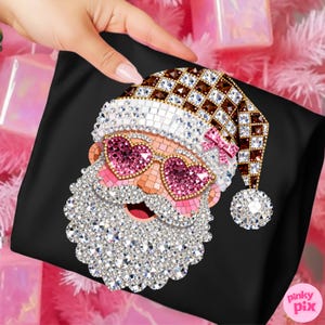 May include: A black fabric pouch featuring a diamond art design of Santa Claus wearing heart-shaped pink glasses and a brown and white chequered hat. The design is embellished with sparkling rhinestones, including a white beard and a pom-pom.