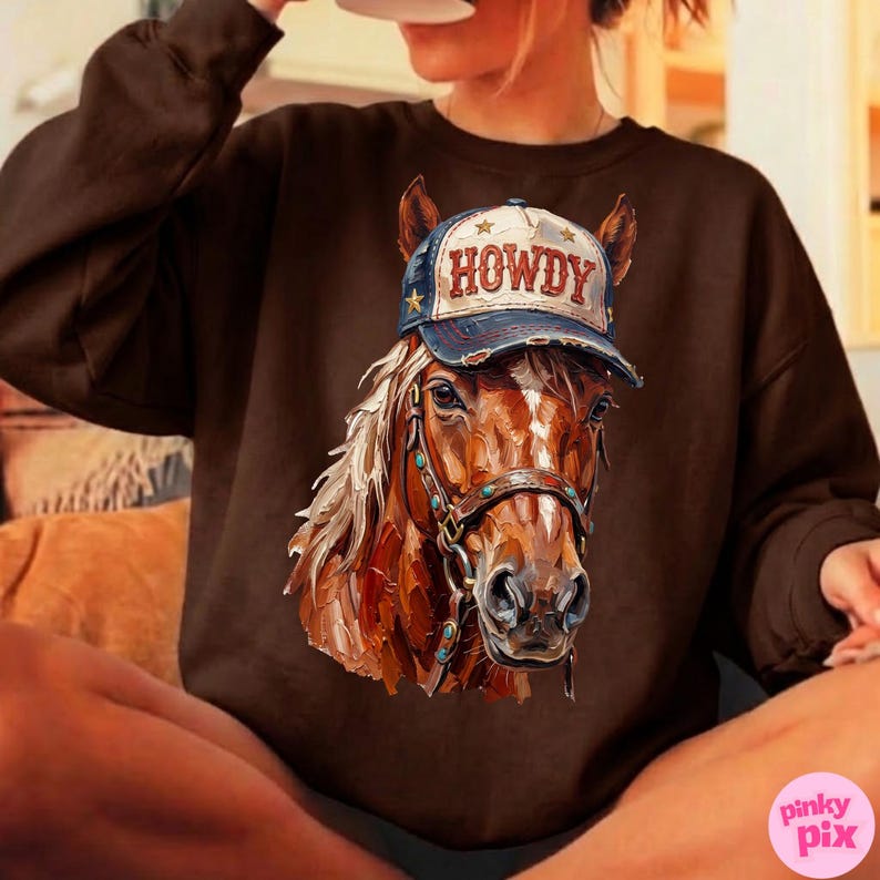 May include: Brown sweatshirt featuring a detailed illustration of a horse wearing a baseball cap. The cap is blue and white with the word "HOWDY" in red. The horse has a bridle with turquoise accents.