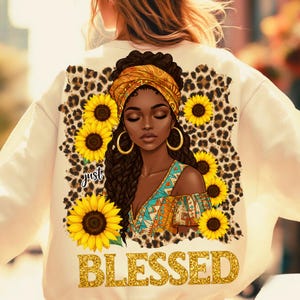 Pu&ograve; includere: Felpa color crema con una grafica di una donna nera con un foulard giallo e orecchini a cerchio dorati, circondata da girasoli e un bordo con stampa leopardata. La parola "BLESSED" &egrave; stampata in lettere glitterate dorate.