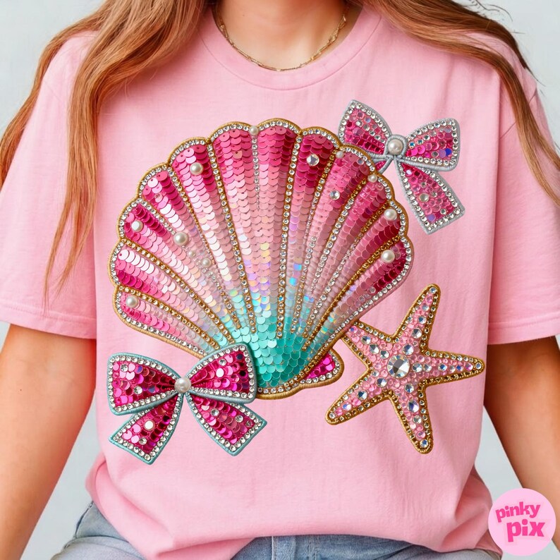 May include: Pink t-shirt featuring a sequined seashell design with pink and teal hues, adorned with pearls and rhinestones. Two sequined bows and a rhinestone starfish complete the design. The text "pinky pix" is in the bottom right corner.