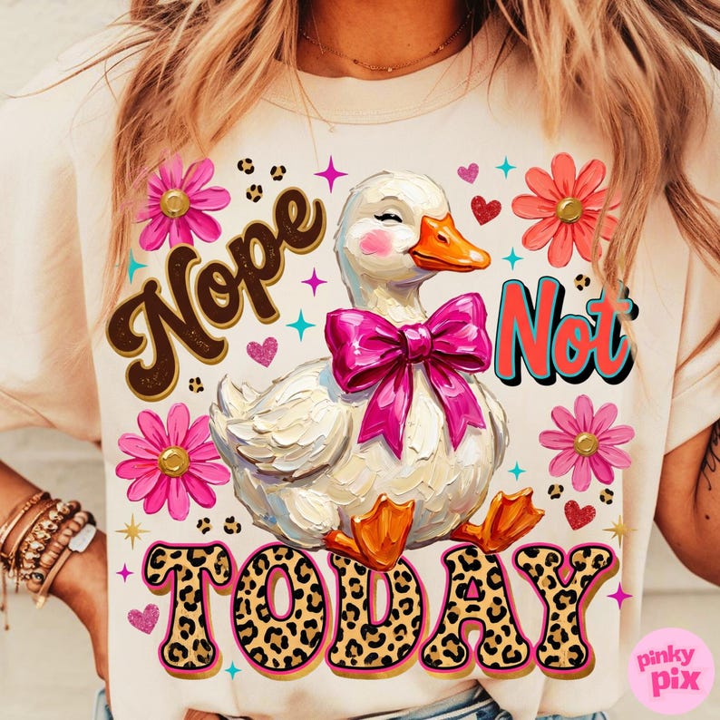 May include: Cream-colored t-shirt with a graphic of a white duck wearing a pink bow, surrounded by pink flowers and hearts. The text "Nope Not Today" is displayed in a playful font with leopard print accents.