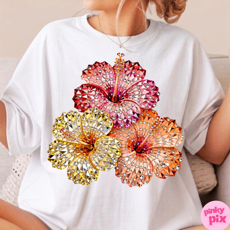 May include: White t-shirt featuring a vibrant floral design. The design showcases three hibiscus flowers in shades of red, pink, orange, and yellow, embellished with sparkling details. The flowers are arranged in a cluster, creating a visually appealing graphic.