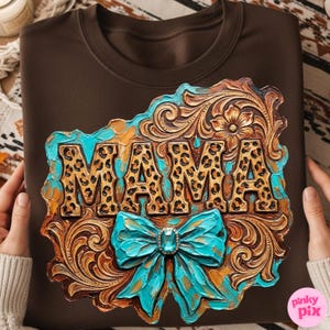 May include: A brown sweatshirt featuring a decorative design with the word "MAMA" in leopard print. The design includes a turquoise bow with a jewel and ornate, carved details in shades of brown and gold.