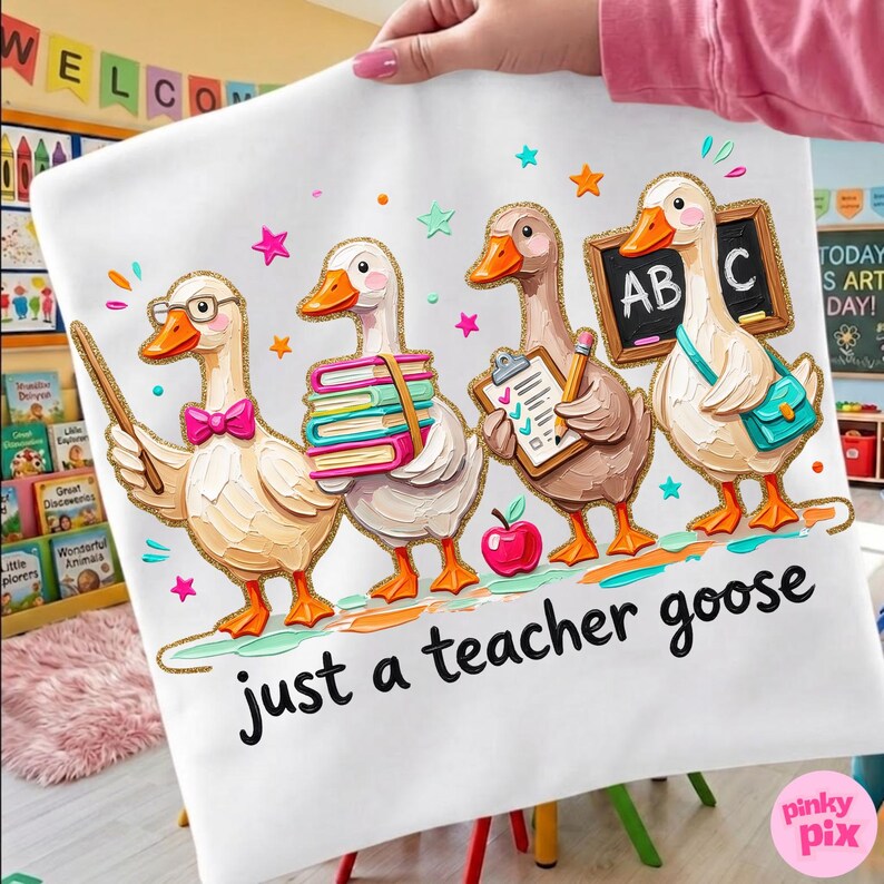 May include: White t-shirt featuring a whimsical illustration of four geese dressed as teachers. One goose wears glasses and holds a pointer, another carries books, a third has a clipboard, and the last holds a chalkboard. The text "just a teacher goose" is below the geese.