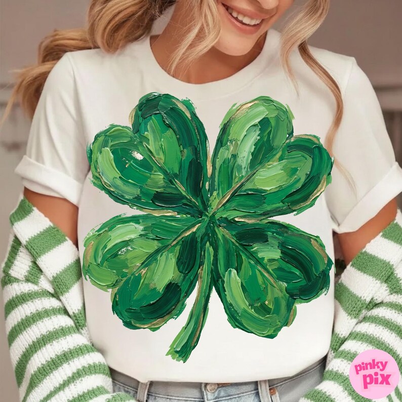 K&ouml;nnte beinhalten: Wei&szlig;es T-Shirt mit einem gro&szlig;en, strukturierten vierbl&auml;ttrigen Kleeblatt-Design in Gr&uuml;n- und Goldt&ouml;nen. Das Kleeblatt ist der Schwerpunkt, mit sichtbaren Pinselstrichen. Das Shirt ist Teil eines St. Patrick's Day-Themas.