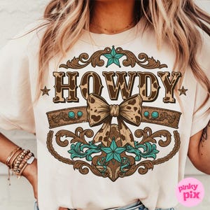 Pu&ograve; includere: Una maglietta color crema con un designo a stampa leopardata marrone e bianca che dice "Howdy" con un fiocco marrone e bianco e dettagli turchesi.