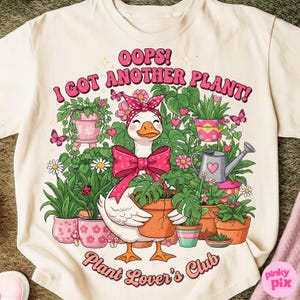 Könnte beinhalten: Cremefarbenes T-Shirt mit einer Cartoon-Gans, die eine rosa Schleife und ein Stirnband trägt und eine Topfpflanze hält. Der Aufdruck lautet "OOPS! I GOT ANOTHER PLANT!" und "Plant Lover's Club" in Rosa. Das Design umfasst verschiedene Topfpflanzen und Schmetterlinge.