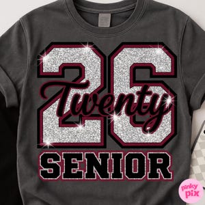 May include: Dark gray sweatshirt with the number "26" in silver glitter, outlined in burgundy and black. The word "Twenty" is in a cursive font, and "SENIOR" is in block letters. A pink and white logo is in the bottom right corner.