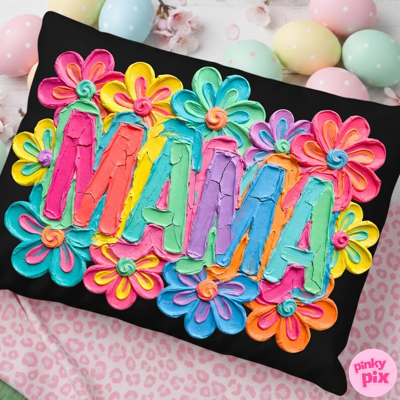 May include: Black decorative pillow with the word "MAMA" in colorful, textured lettering, surrounded by vibrant, multi-colored flowers. The pillow is a square shape.