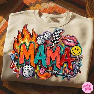 May include: Beige sweatshirt with a colorful graphic design. The design includes the word "MAMA" in graffiti style, flames, dice, a lightning bolt, lips, a smiley face, and barbed wire.