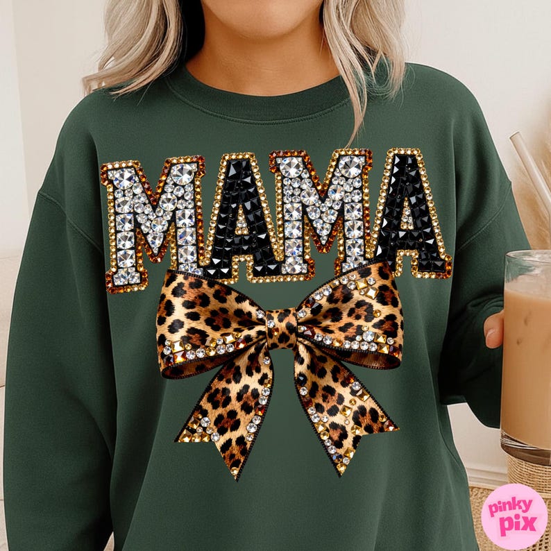 May include: A dark green sweatshirt with the word "MAMA" in large, jeweled letters. Below the text is a leopard print bow with crystal embellishments. The sweatshirt is a casual, stylish garment.