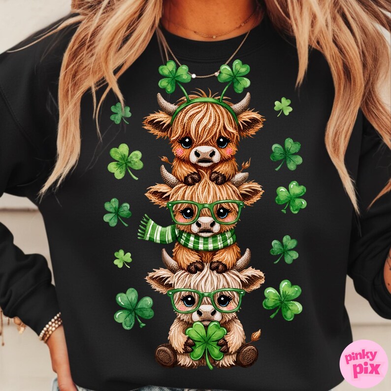 May include: Black sweatshirt featuring a stacked design of three cartoon Highland cows. The cows are brown and tan, wearing green glasses, scarves, and shamrock headbands. Green shamrocks are scattered around the cows.