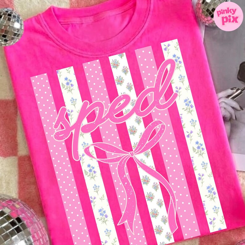 May include: A bright pink t-shirt with the word "sped" in a cursive font. The design includes vertical stripes in pink, white polka dots, and floral patterns, along with a bow at the bottom. The shirt is a vibrant and eye-catching piece.