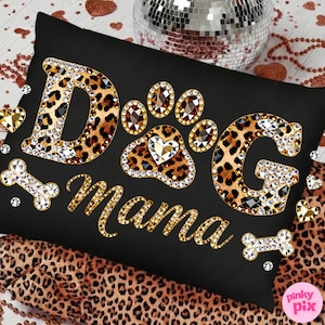 May include: Black rectangular pillow with the words "DOG Mama" in gold and rhinestone embellishments. The letters "DOG" are leopard print with rhinestone borders. A paw print and bone shapes are also decorated with rhinestones.