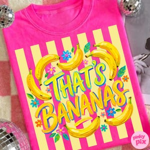 Pu&ograve; includere: Una maglietta rosa acceso con un design a righe gialle e bianche. La maglietta presenta la frase "That's Bananas" in un carattere giocoso, circondata da illustrazioni di banane gialle e fiori colorati.